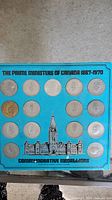 Blue display card with 15 commemorative medallion coins of Canadian Prime Ministers arranged in a 4x4 grid with one coin missing position.