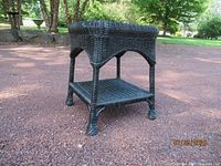 Front three-quarter view of black square wicker side table showing top and shelf