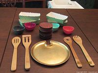 All items grouped on table: wooden utensils, gold plate, coaster stack, silicone bowls, paper bakeware