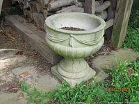 Front view of one concrete planter showing draped swag design and pedestal base