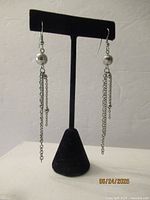 Pair of long chain drop earrings with bead accent on display stand