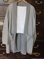 Front view of reversible ash grey jacket with white pants folded underneath showing pockets and drape