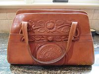 Front view brown leather floral-embossed handbag