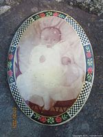 Front of oval infant photo frame showing floral border