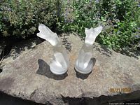 Both Lalique frosted glass figurines on stone surface