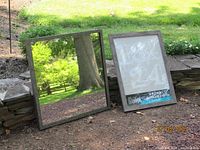 Square mirror and packaged Studio Decor frame leaning against stone wall