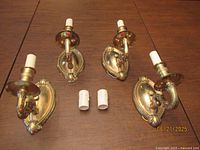 Four brass sconces and two white candle sleeves on table
