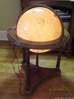 Illuminated globe on wooden stand with cord visible