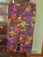Brown floral Elena Miro slacks hung on dresser