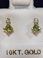 Front view of both earrings showing square-cut peridot with round diamonds above, set in 10K gold.