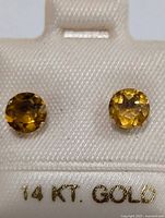 Front view of two round faceted citrine stones set in 14K gold studs on white card marked 14KT GOLD.