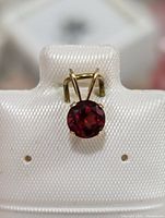 Close-up of the garnet pendant showing the round faceted gemstone in 14K gold setting.