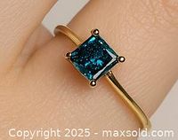 Ring front view on neutral background showing square blue diamond and yellow gold band