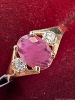 Close-up of ring front displaying oval pink-red natural ruby and one round diamond
