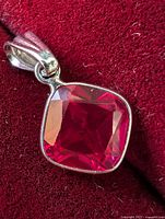 Close-up of cushion cut ruby and bezel setting on red velvet background