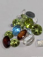Photo showing a group of various faceted genuine gemstones of different colors and cuts on a white background.
