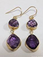 Front view of pair of silver dangle drop earrings with two amethyst stones each, showing the purple faceted gemstones and gold-tone bezels.