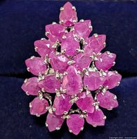 Top-down view showcasing the ruby cluster flower design and silver prong settings on a dark background.