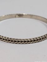 Close-up of silver braided pattern texture on the bangle bracelet.