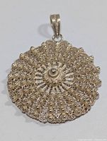 Front view of the large round silver pendant showing intricate filigree and granulation pattern.
