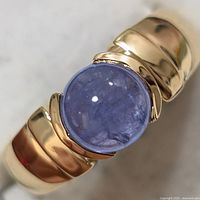 Close-up top view showing light blue-violet round tanzanite stone set in a polished silver band with smooth bezel setting.