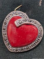 Heart-shaped red agate pendant bordered and accented with marcasite stones, shown on dark background.