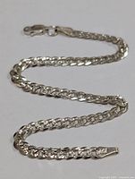 Close-up image of a shiny silver chain bracelet laid flat showing chain links and clasp, highlighting .925 silver stamp.