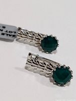 Pair of silver earrings with round green onyx stones, showing textured silver detail and stone setting