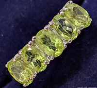 Close-up of the five faceted peridot stones on the silver ring from a top angle showing details and settings.