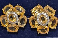 Close-up photo of the front face of the pair of citrine and silver flower-shaped earrings showing gemstone arrangement and design.