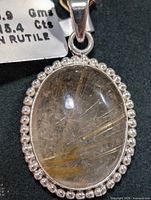 Close-up front view of the pendant displaying the rutilated quartz with golden needle inclusions and beaded silver border.