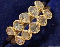 Close-up front view of silver ring showing seven pear-shaped rough-cut diamonds in a row, set in silver bezels.