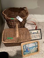 Full set showing all baskets and framed needlepoint samplers arranged together on carpeted floor.