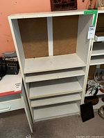 Front view of the white bookshelf showing five shelves and visible wear.