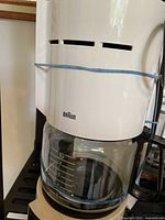 Close-up of Braun coffee maker with glass carafe showing measurement marks and brand logo.