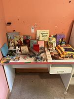 Photo of entire lot arranged on a white desk with orange background showing the various books, marbles, toys, and games.