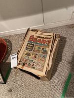 Photo showing a large box filled with many vintage Beano comic books, front comic visible is an issue of The Beano featuring Dennis the Menace.