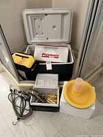 Igloo Playmate cooler with other coolers, utensils, bungee cords, plates and cups displayed on floor