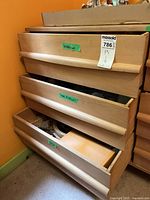 Wooden dresser with three drawers partially open containing crafting supplies.