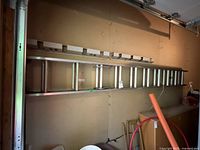 Full view of the aluminum extension ladder horizontally positioned on support, showing multiple rungs and part of the locking mechanism.