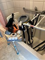 Various home care items including bed rail, shower chair, canes, commode seat and bed pans shown in bathroom corner.