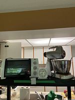 Wide view of kitchen appliances on counter including Toastmaster toaster oven, Westclox alarm clock, and Sunbeam Mixmaster stand mixer