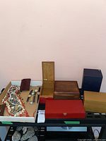 Shows collection of music boxes, costume jewelry, and wristwatches arranged on a shelf