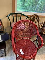 Red wicker chair and green metal stool placed next to each other inside a room with natural light from a window.