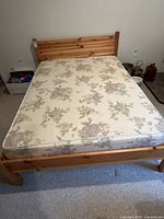 Top view of full pine wood bed frame with floral mattress on top.