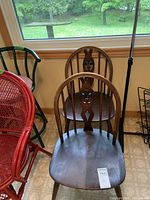 Pair of dark stained wooden chairs with curved rounded backs and carved central spindles, showing wear.