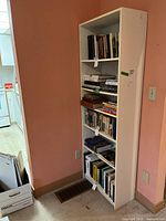 Front view of the white bookshelf showing the five shelves filled with books.