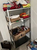 Photo showing full view of metal frame shelf unit with glass shelves and cardboard boxes placed on shelves.