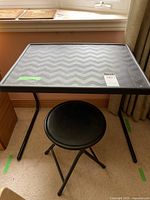 Full view of Table-Mate folding table with chevron-patterned plastic top and black folding stool underneath.