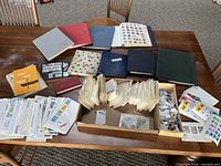 Overview photo of the collection showing multiple stamp albums, loose envelopes, and boxes containing bundled stamps.